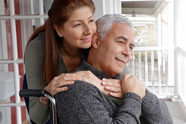 Woman hugging a man in a wheelchair.